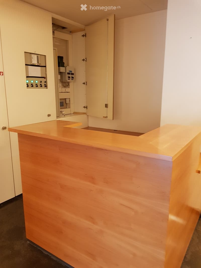 Wooden reception desk with 2 open doors behind the desk, electrical panels
