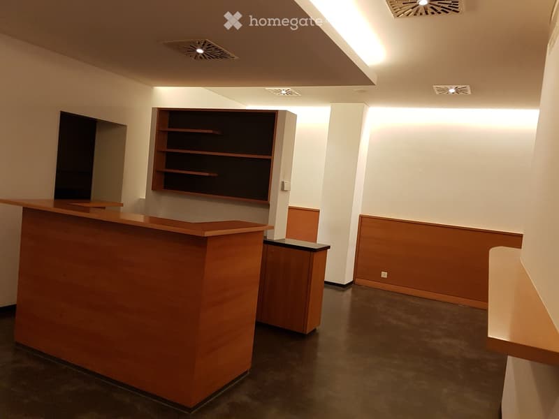 Large open room with wooden shelves, wooden counter, and tiled flooring