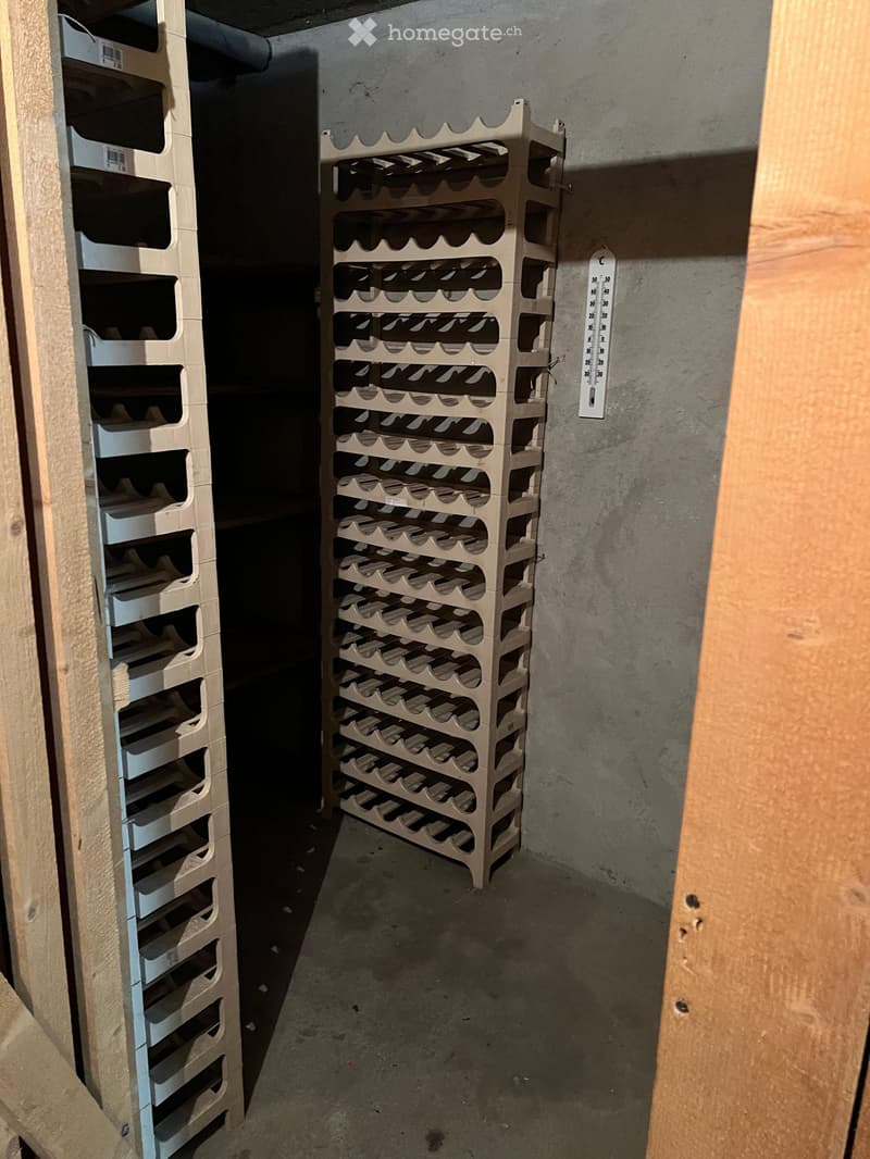 Empty storage room with wooden shelving units and a temperature gauge on the wall.