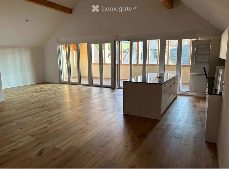 Empty room with wooden flooring, large sliding glass doors, and a small kitchen island with cabinets.