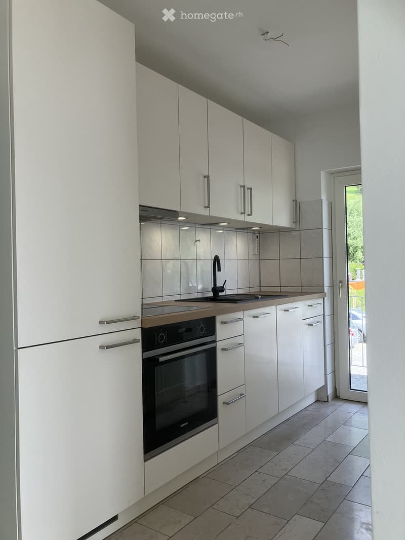 Modern kitchen with white cabinets, stainless steel appliances, and a wooden countertop.