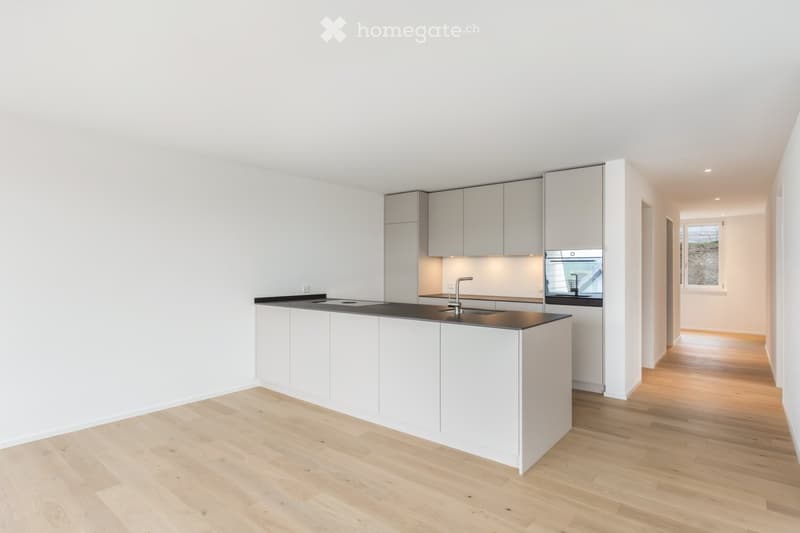 Modern kitchen with white cabinets, black countertop, wooden flooring, and built-in appliances.
