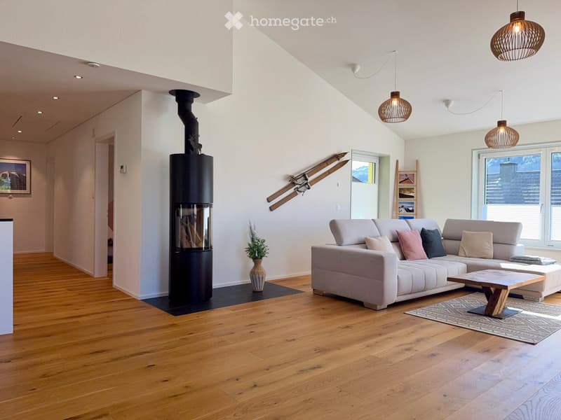 Modern living room with light-colored sofa, wooden coffee table, fireplace, and large windows.