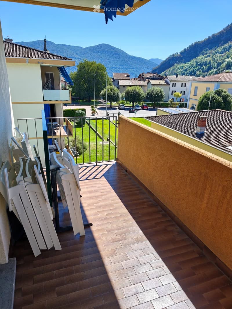 Balcony with wooden flooring, metal railing, and scenic mountain view in the background.