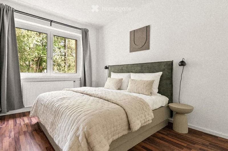A well-lit bedroom with a large bed, pillows, and a blanket, positioned near a window with curtains. A small stool sits beside the bed, and a piece of wall art is mounted on the wall.