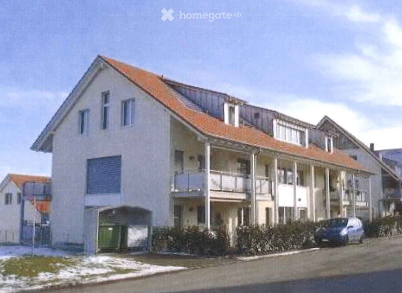 Two-story house with a red-tiled roof, multiple windows, and a covered balcony area on the upper floor.
