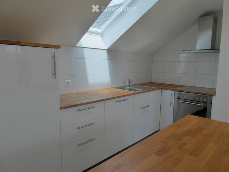 Modern kitchen with white tiled walls, wooden countertops, stainless steel appliances, and a skylight window above the sink.
