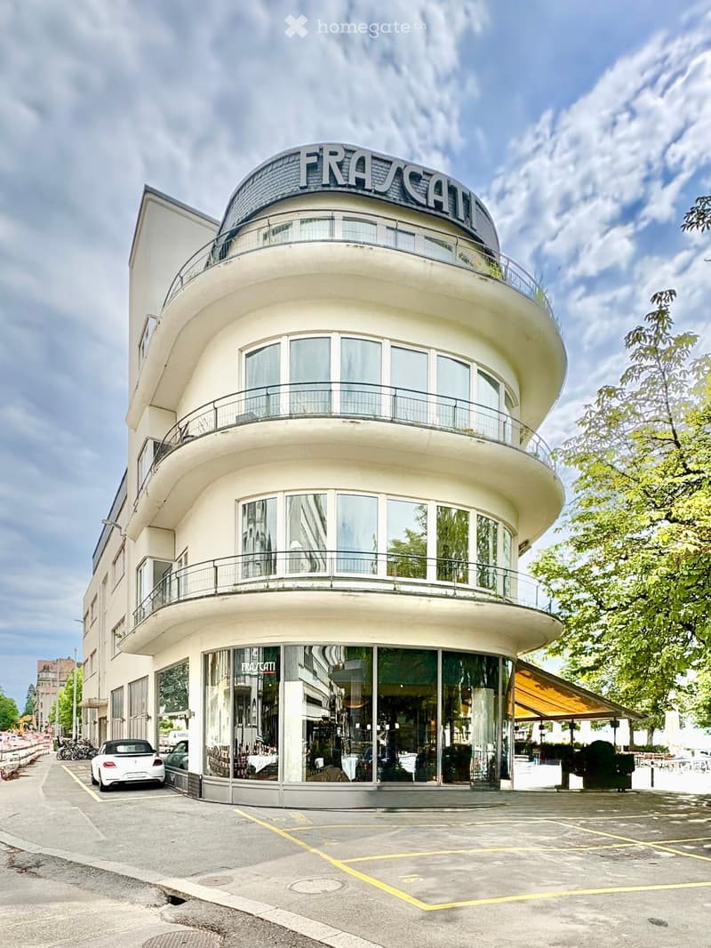 Modern, curved building with large glass windows and balconies, featuring the sign "FRASCATI" on the roof.