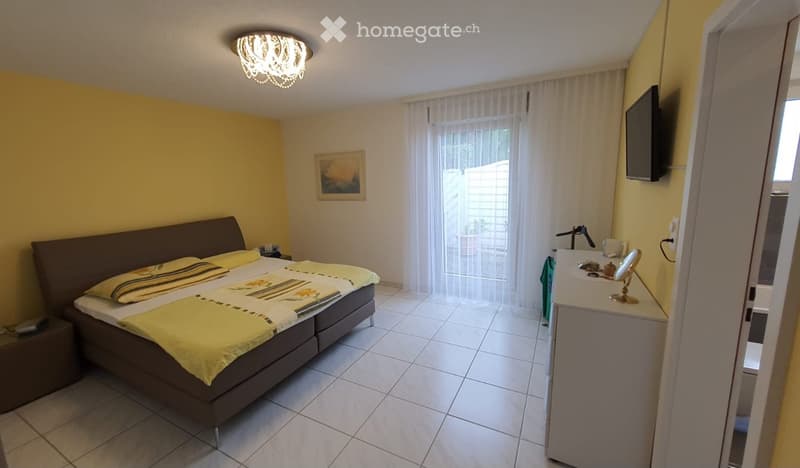 bedroom with bed, nightstands, television, and window with curtains