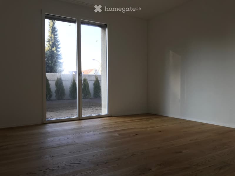 Empty room with wooden flooring and large sliding glass doors leading to an outdoor area.