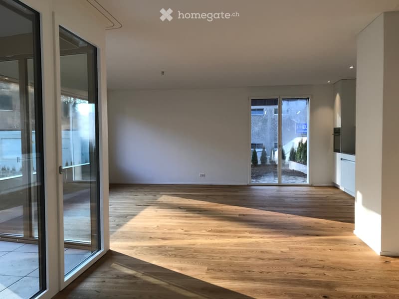 Empty room with wooden flooring, large glass sliding doors, and white walls.