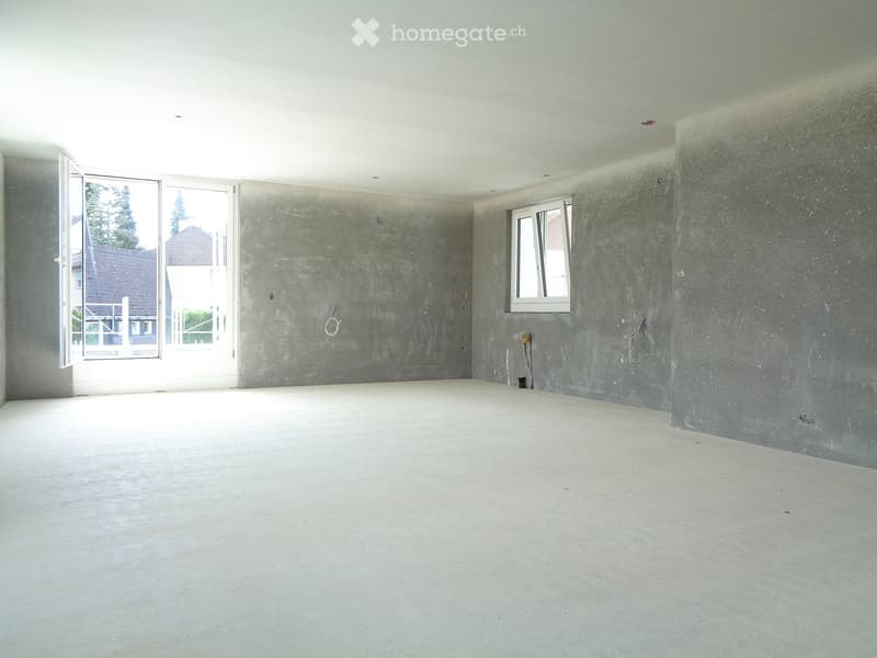 Empty room with bare concrete walls and floor, featuring a large window and an open doorway leading outside.