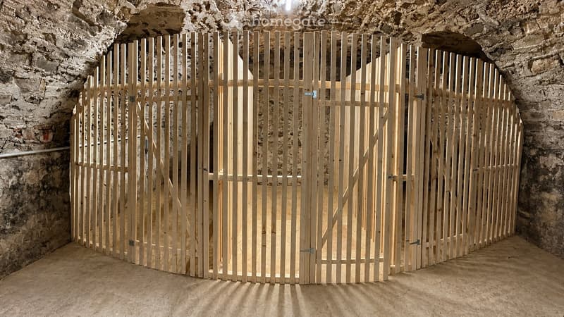 Empty room with unfinished wooden walls and a wooden floor, featuring a large wooden gate in the center.