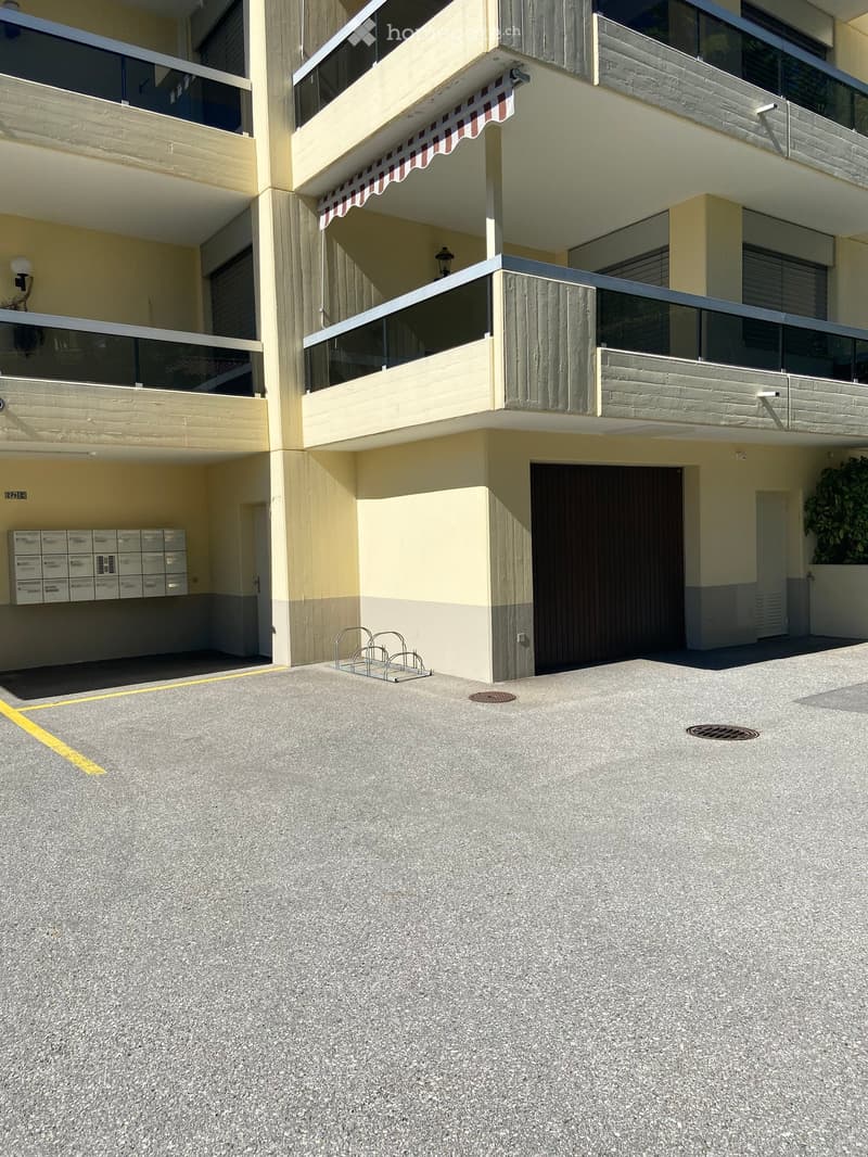 Multi-story residential building with balconies, mailboxes, and a covered entrance area.