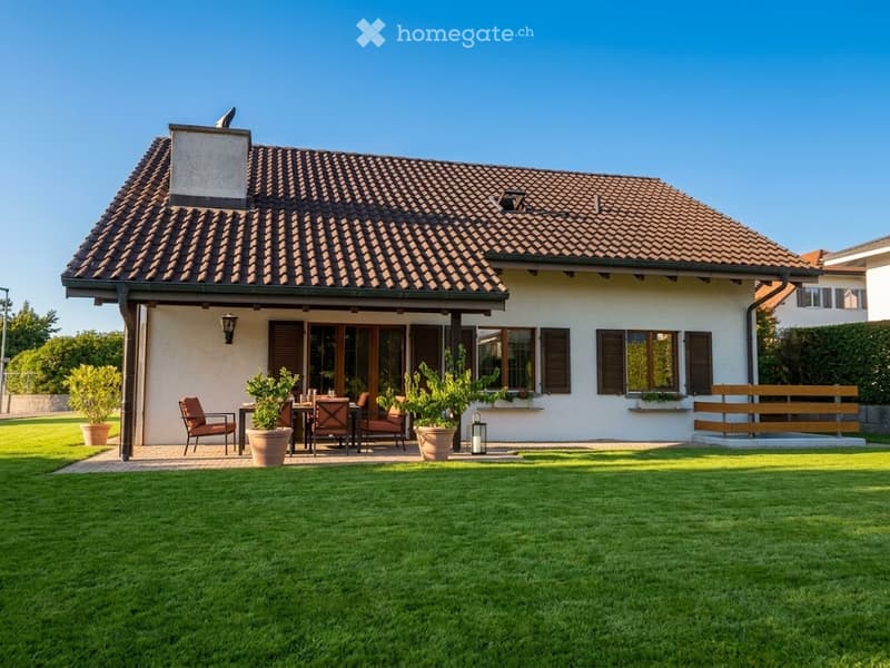 Single-story house with a tiled roof, large windows, and a covered patio area with outdoor furniture.