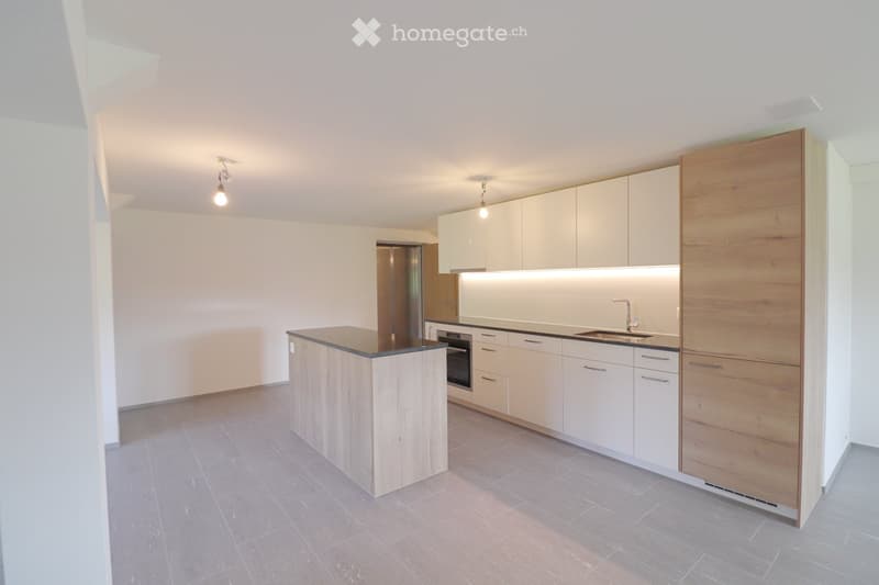 Modern kitchen with light-colored cabinets, a central island, and built-in appliances including an oven and sink.