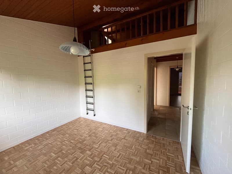 Empty hallway with wooden herringbone flooring, white brick walls, a hanging light fixture, and a narrow staircase leading to an upper level.