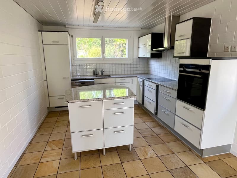 Modern kitchen with white cabinets, granite countertop, tiled floor, and stainless steel appliances including an oven and dishwasher.