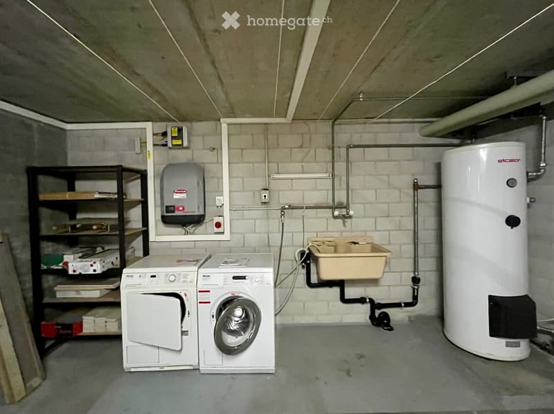 Utility room with white brick walls, concrete floor, washing machine, dryer, water heater, and metal shelving unit.