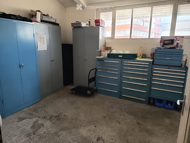 Workshop or storage room with tool cabinets, a small cart, and various storage items.