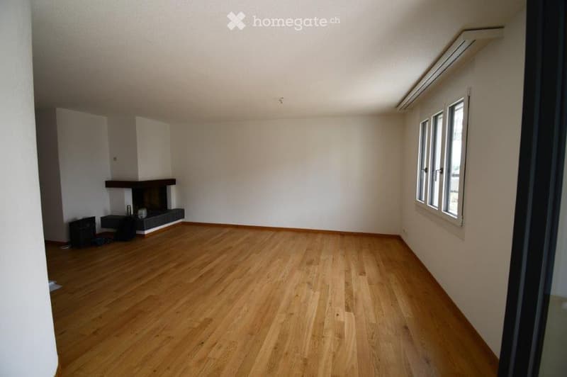 Empty room with wooden flooring, white walls, and a fireplace against one wall. No furniture or equipment present.