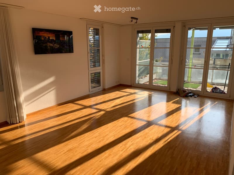 Empty room with wooden flooring, large windows, and a balcony door leading to a small outdoor area.
