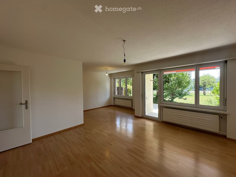 Empty room with wooden flooring, white walls, large windows, and a door. No furniture or equipment present.