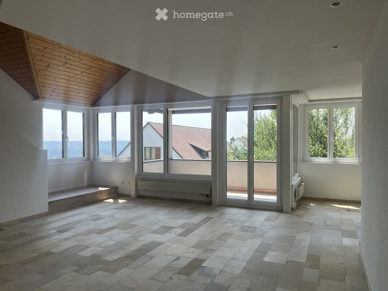 Empty room with large windows and sliding glass doors leading to a balcony, tiled floor, and wooden ceiling beams.