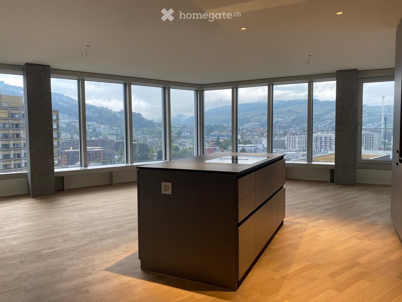 Modern kitchen with a central island, large windows offering a scenic city and mountain view, and wooden flooring.