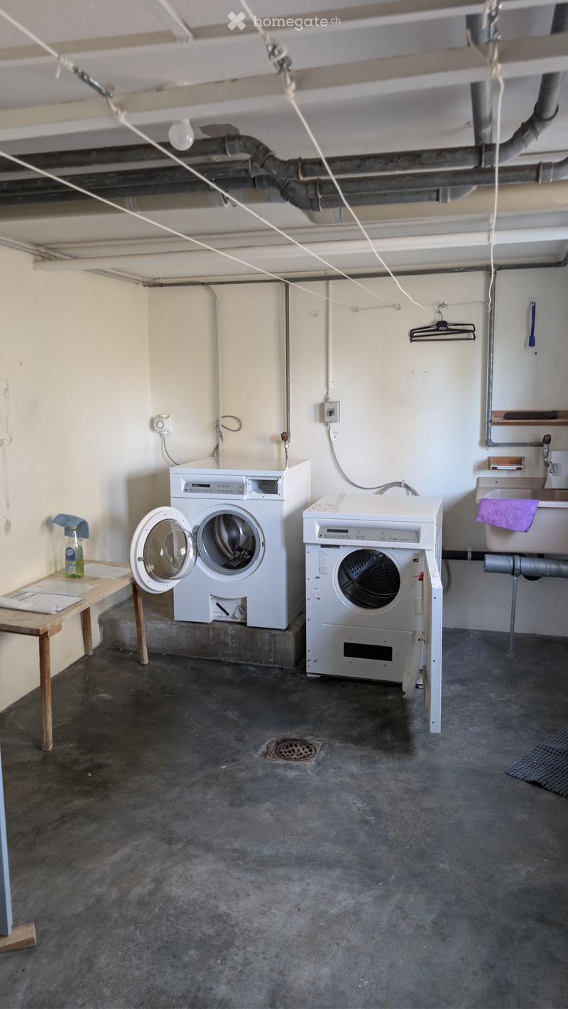 Utility room with a washing machine, dryer, small table, and sink.