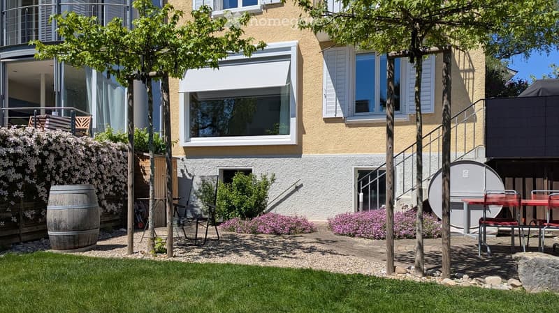 Garden area with a patio, outdoor furniture, and a view of the house with balconies and windows.