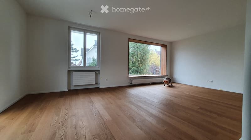 Empty room with wooden flooring, large windows, and radiators. No furniture or equipment present.