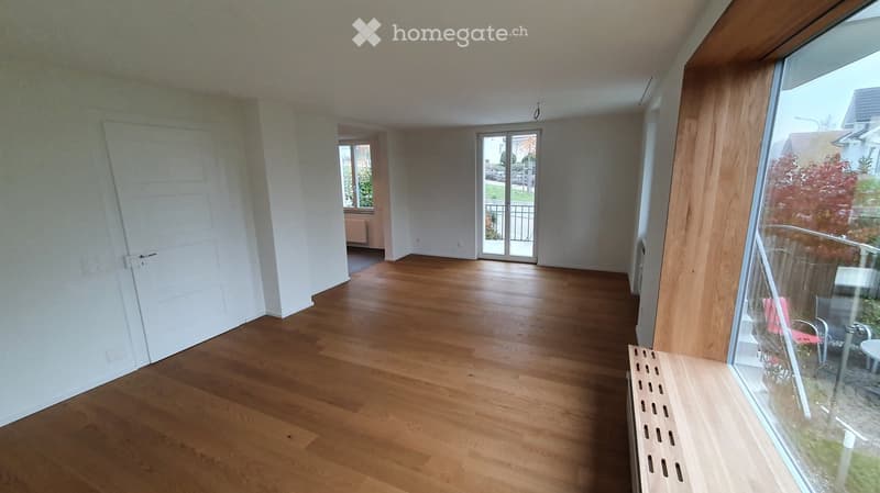 Empty room with wooden flooring, white walls, and large windows. No furniture or equipment present.