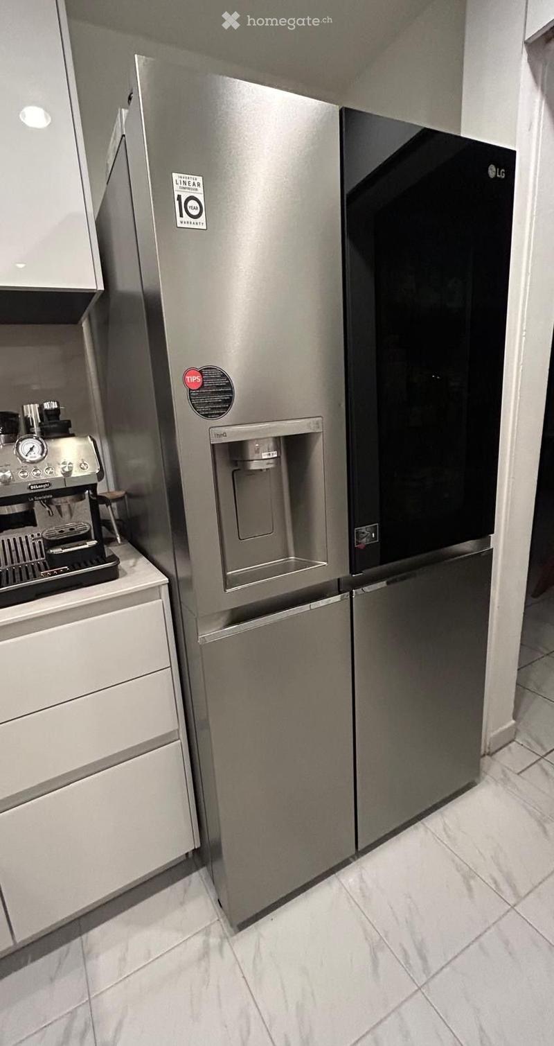 Modern kitchen with stainless steel refrigerator and coffee machine on a countertop.