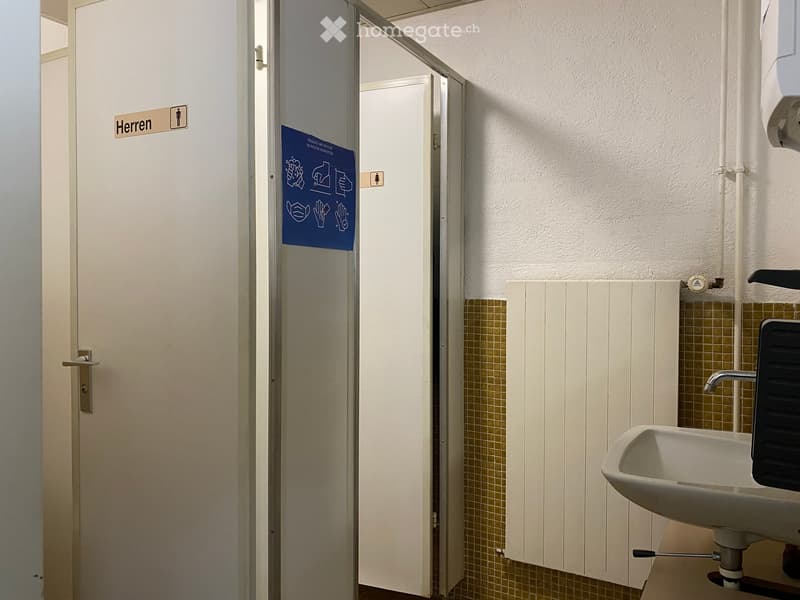 Public restroom with a sink, faucet, and a door labeled 'Herren' (Men's).