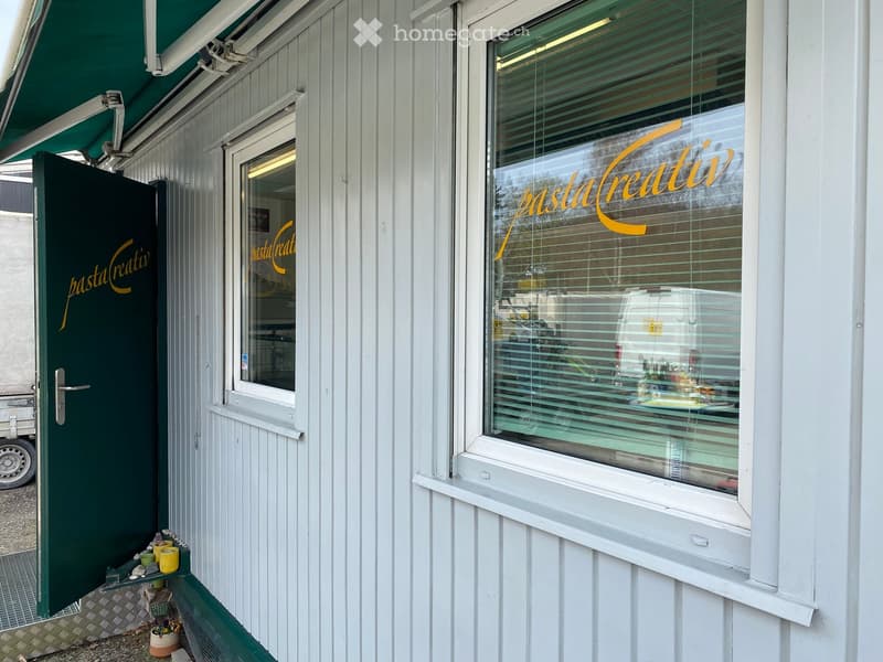 Facade of a restaurant named "pastaCreativ" with a green door and window displaying the name. Small decorative items are placed near the entrance.