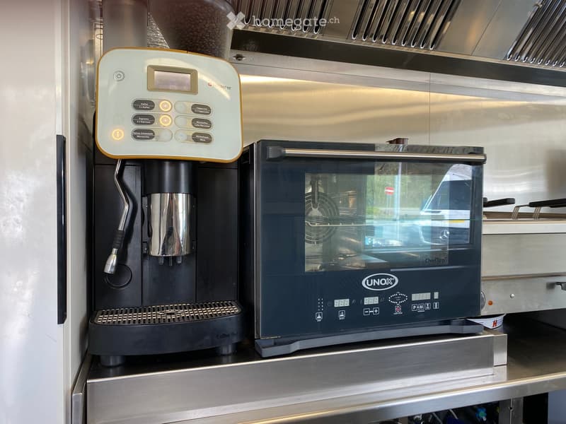 Modern kitchen with a coffee machine and an oven, both featuring digital displays and stainless steel finishes.