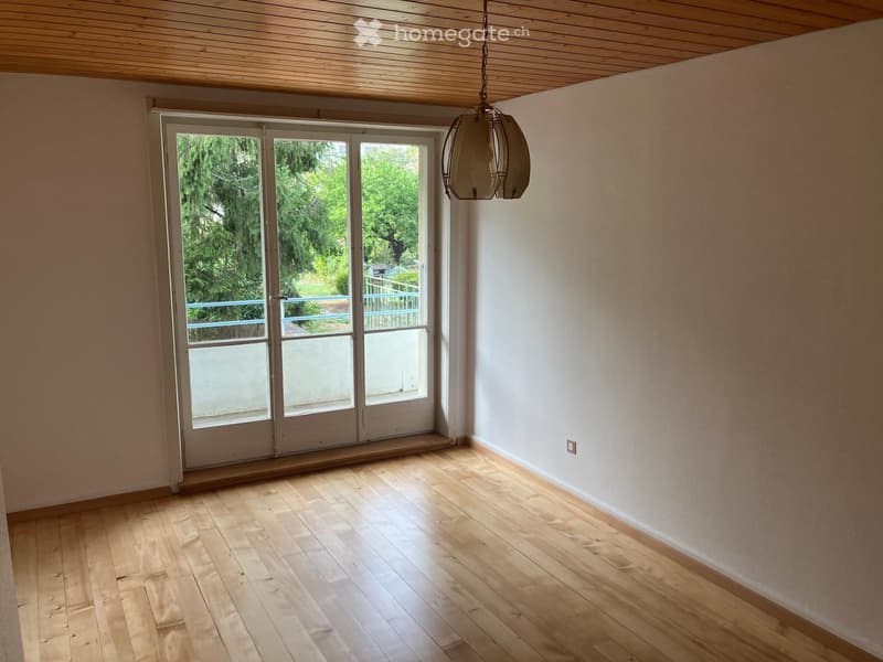 Empty room with wooden flooring, white walls, and a large sliding glass door leading to an outdoor area.