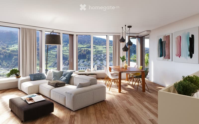 Modern living and dining area with large windows offering scenic views, a sectional sofa, dining table, chairs, and decorative items.