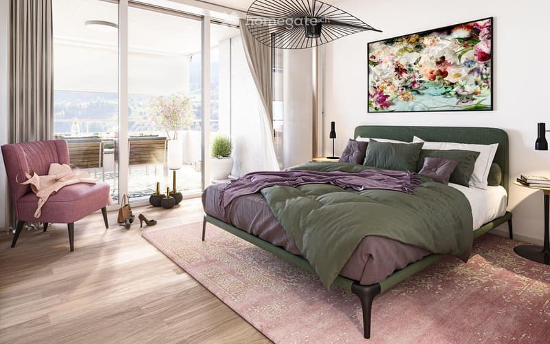 Modern bedroom with a large bed, green headboard, pink armchair, side table, and a scenic view through large windows.