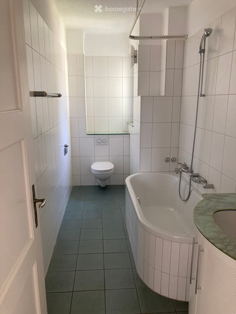 Bathroom. Modern bathroom with white tiles, a bathtub, toilet, sink, and a glass shower enclosure.