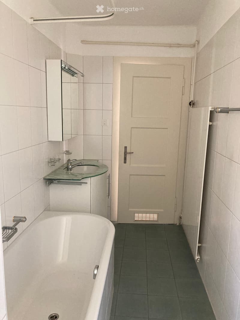 Bathroom. Bathroom with a white bathtub, a glass sink with a modern faucet, a mirrored cabinet, and tiled walls and floor.