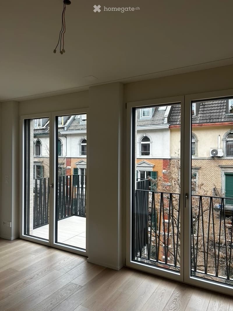 Empty room with wooden flooring and large sliding glass doors leading to a balcony. No furniture or equipment present.