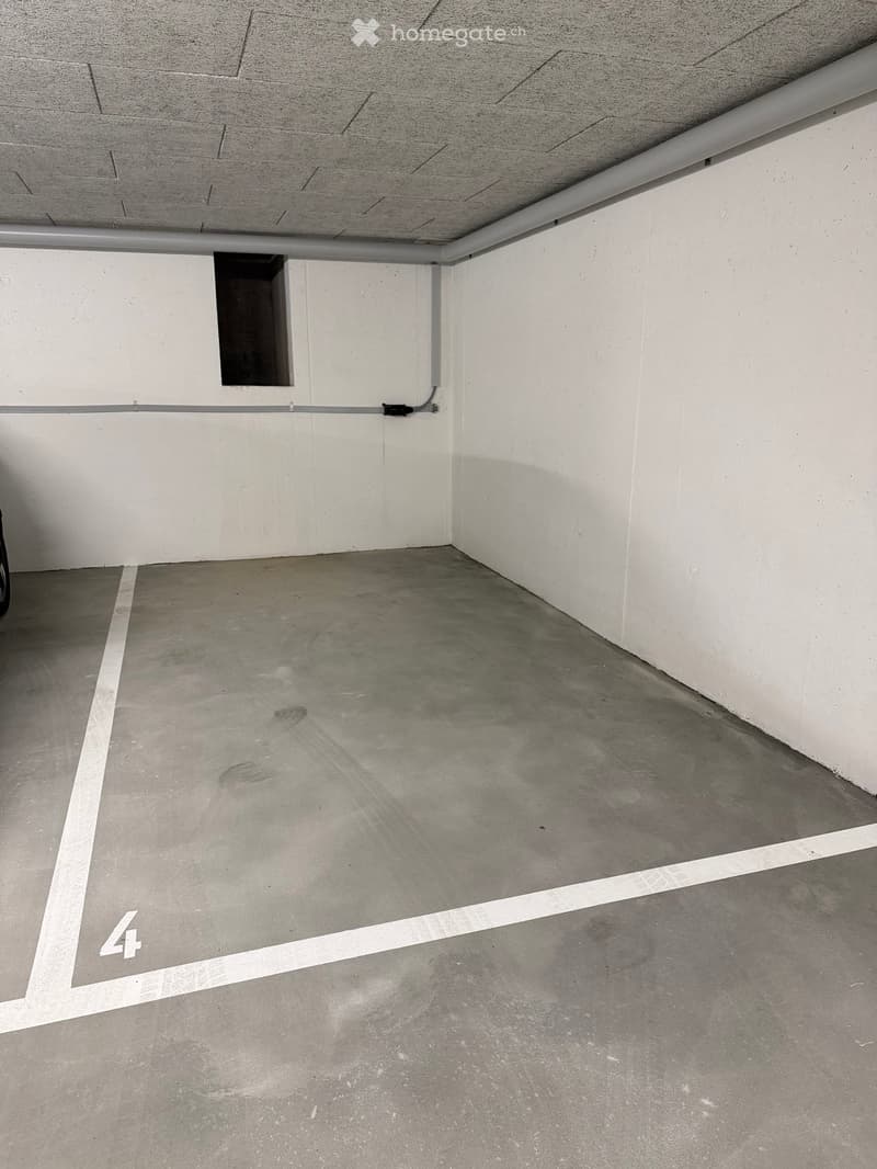 Empty underground parking space with concrete floor and white walls, marked with number '4'.