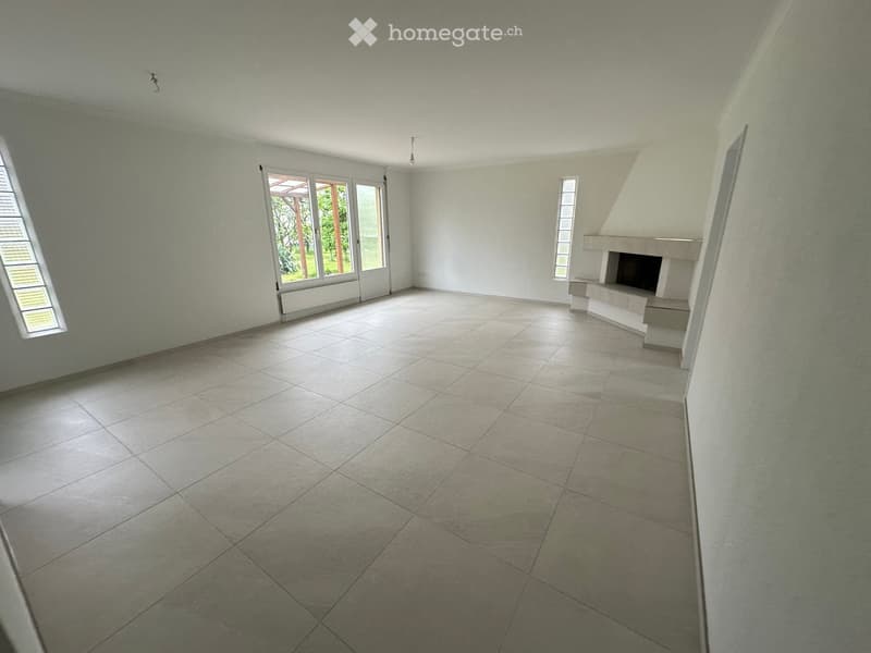 Empty room with tiled floor, white walls, large windows, and a fireplace.