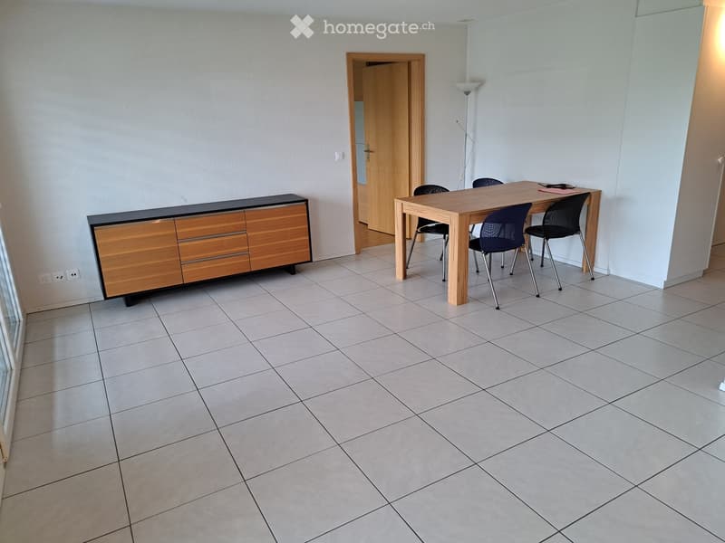 Dining room with tiled floor, wooden dining table, four chairs, and a wooden cabinet with drawers.