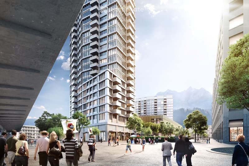 A modern high-rise building with numerous windows and balconies, surrounded by trees and a pedestrian area with people walking.