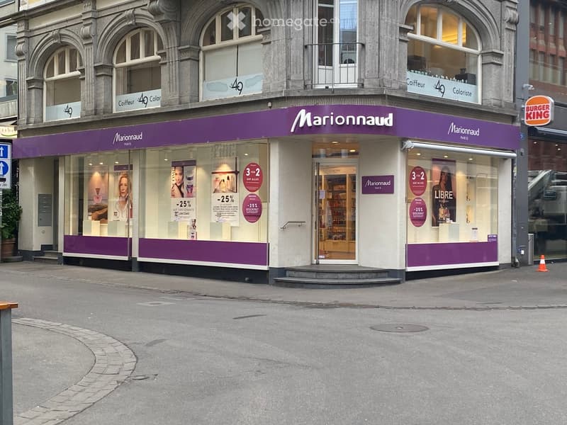 A Marionnaud beauty store with purple signage, large windows displaying cosmetics, and promotional posters for discounts on Lancôme products.