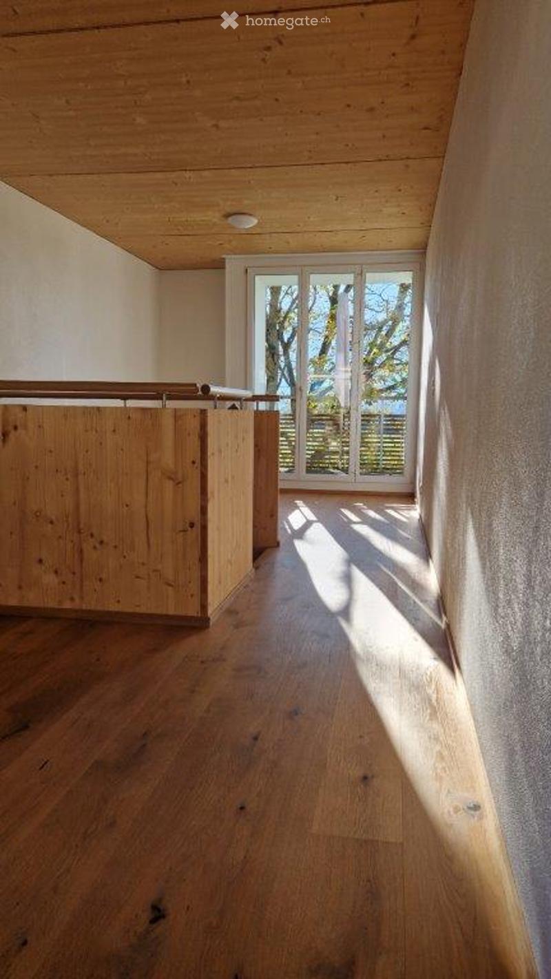 Bright, unfurnished room with wooden flooring and a wooden ceiling. Large window with a view of the outdoors, allowing natural light to fill the space.