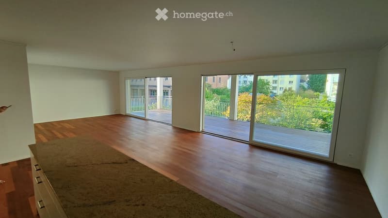 Empty room with wooden flooring, large sliding glass doors leading to a balcony, and white walls.